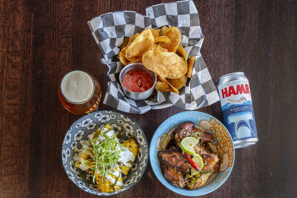 Sampling of food from Revival Brewing's menu including wings, chips, and grilled corn paired with HAMR Pale Ale